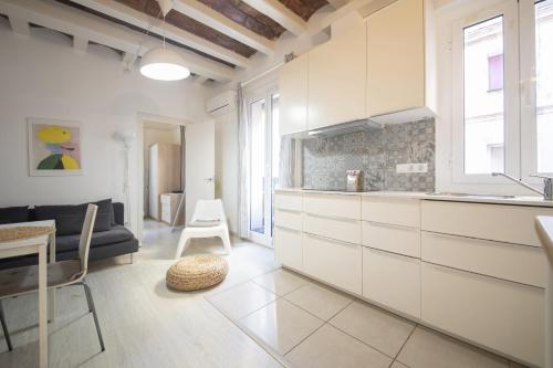 Catalunya Casas Lovely apartment central Barcelona 100m to beach! في برشلونة: مطبخ وغرفة معيشة مع دواليب بيضاء