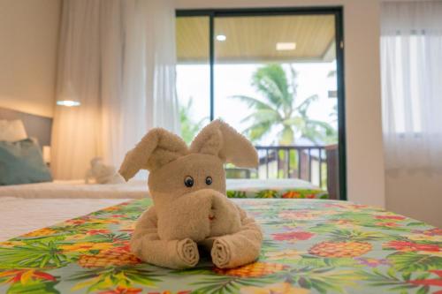 un conejo de peluche sentado en la parte superior de una cama en Marulhos Suítes Resort by MAI, en Porto de Galinhas