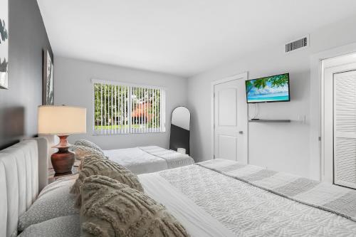 Habitación blanca con 2 camas y TV. en Expansive wiith pool access, 10 mins from Pompano Beach en Pompano Beach