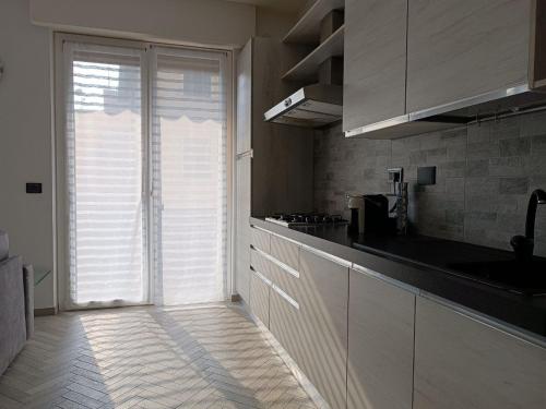 una cocina con armarios blancos y una gran puerta corredera de cristal en GF Holiday Suite en Varazze