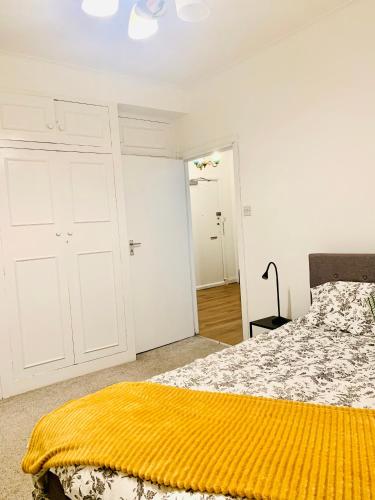 a bedroom with a bed with a yellow blanket on it at Cosy 2 bedroom apartment in Swiss Cottage. in London