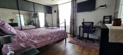 1 dormitorio con cama, escritorio y espejo en La Petite Locherie, en Oradour-Saint-Genest