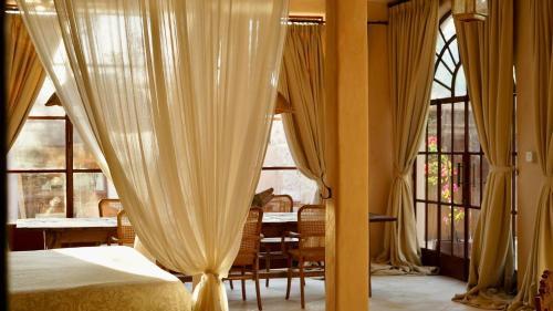 1 dormitorio con cortinas y comedor con mesa en Villa Pi Luxury Uluwatu Bali, en Uluwatu