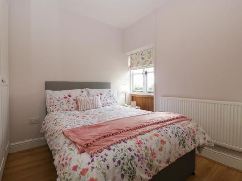 a bedroom with a bed with a pink comforter and a window at The Pheasant Two in Usk