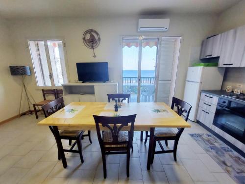 uma cozinha e sala de jantar com mesa e cadeiras em La riva del mare em Santa Teresa di Riva