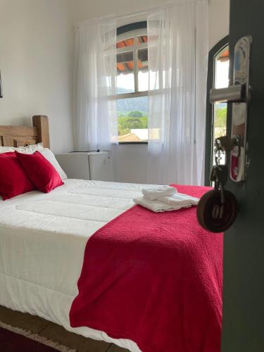 a bedroom with a large bed with a red blanket at Pousada Encanto de Tiradentes in Tiradentes