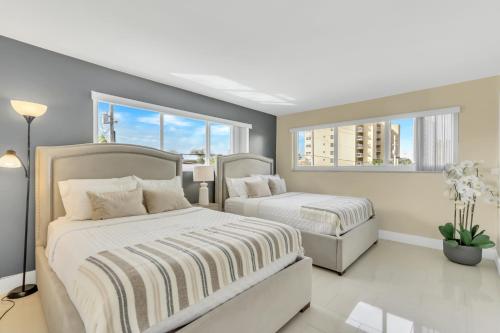 Un dormitorio con dos camas y dos ventanas. en Sunny Pompano Beach with pool access, en Pompano Beach