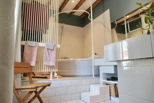 ein Badezimmer mit einer Badewanne, einem Tisch und einem Stuhl in der Unterkunft La Cense - Mélin in Jodoigne