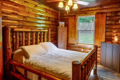 a bedroom with a bed in a log cabin at Secluded Cabin with On-Site Creek and Trails! 