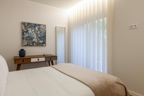 a white bedroom with a bed and a window at Casa do Alcaide - Minhos Guest in Braga