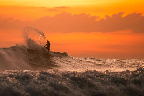 a man riding a wave on a surfboard in the ocean at Akih Pods Hostel in Santa Teresa Beach