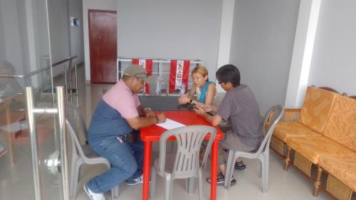 a group of people sitting at a red table at Picuro Lodging House in Iquitos