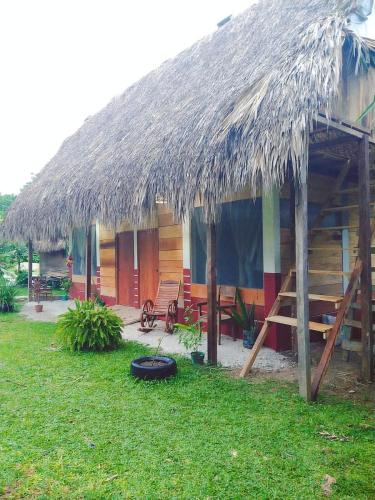a hut with a grass roof and a yard at Topche, Centro Ecoturístico in Lacanjá