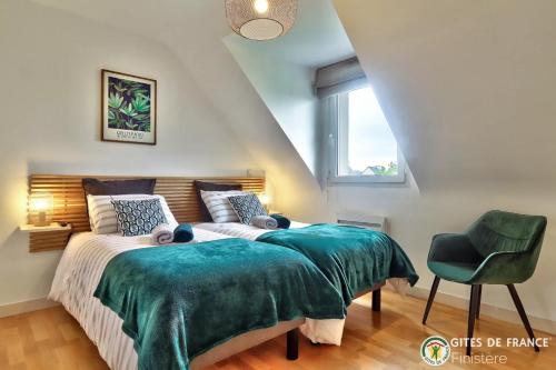 1 dormitorio con 1 cama con manta verde y silla en La Rose des Vents, en Carantec