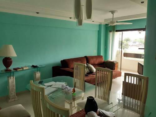 - un salon avec une table et des chaises en verre dans l'établissement Apartamento inteiro na Enseada, à Guarujá
