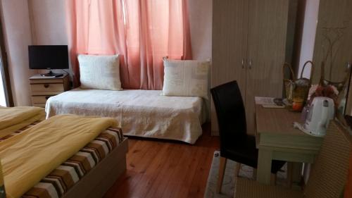 a bedroom with two beds and a desk and a table at Guest House Dara in Tsarevo