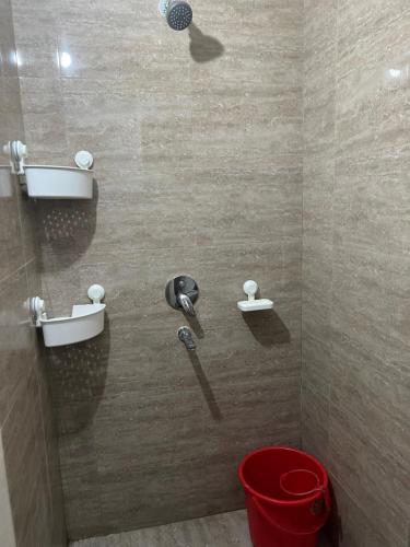 a shower with a red bucket in a bathroom at Tani s Homestay in Bāruipur