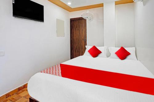 a bedroom with a bed with red pillows and a tv at Super OYO Flagship 81158 Hotel Aditya Inn in Patna