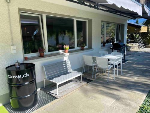 a patio with a bench and a table and chairs at See und Berge Garden in Faulensee