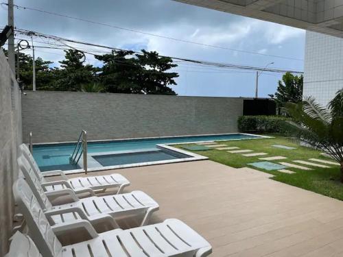 a group of white lounge chairs next to a swimming pool at Flat a beira mar Recife in Recife