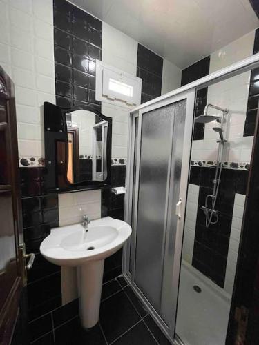 uma casa de banho em preto e branco com um lavatório e um chuveiro em Apartment Oufella em Tamraght Ouzdar