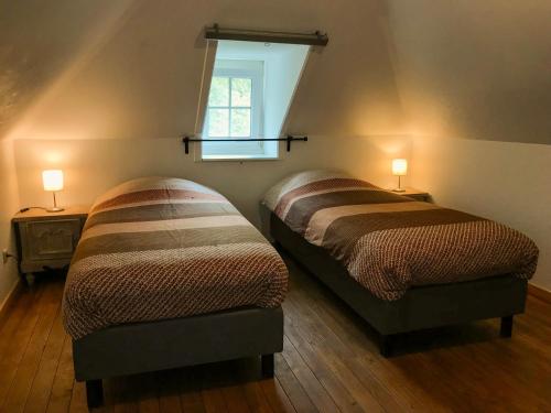 two beds in a room with two lamps on the wall at Heidebos in Het Laar