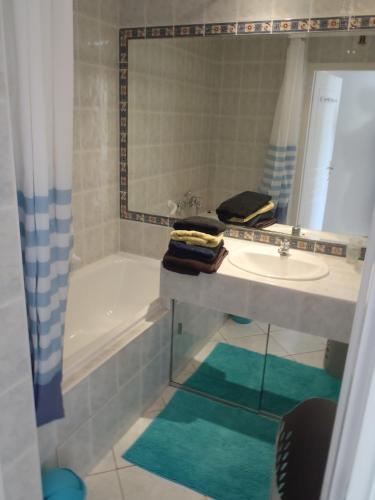 une salle de bain avec un lavabo, une baignoire et un miroir dans l'établissement Appartement Les Alizés, à Juan-les-Pins