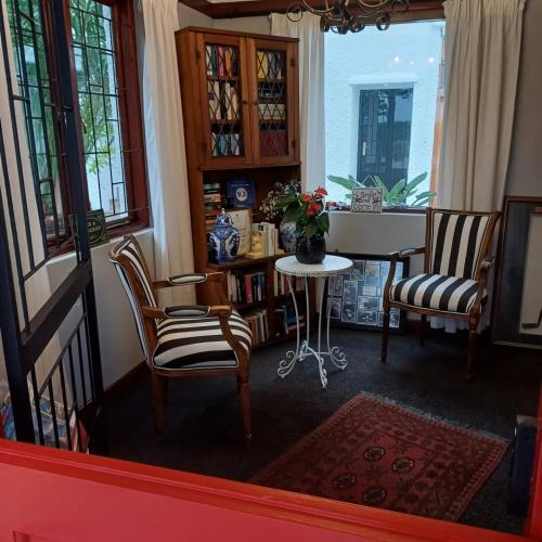 a living room with two chairs and a table at Mulligans Guest Lodge in Hermanus