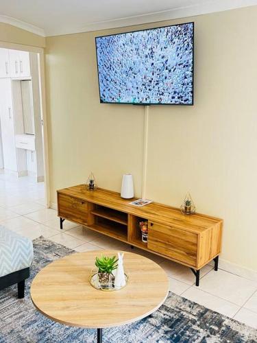 a living room with a table and a tv on the wall at Luba Suite in Durban