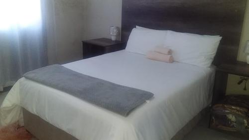 a bedroom with a large bed with white sheets and pillows at JBC Guest House in Bushbuckridge