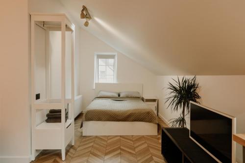 a white bedroom with a bed and a tv at Old brick boutique apartments in Klaipėda