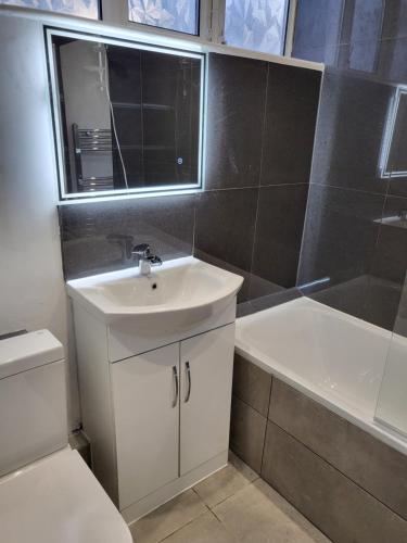 a bathroom with a sink and a tub and a toilet at The Sydenham Snug in Forest Hill