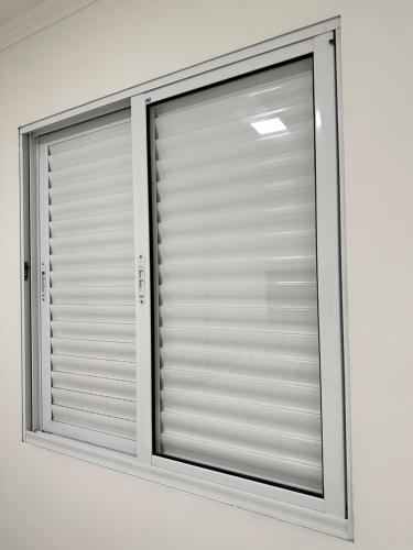 a window with blinds on a white wall at Hotel Aeroporto Congonhas 4 in Sao Paulo