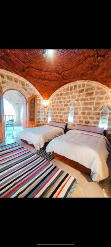 a bedroom with two beds and a stone wall at Pidgeon Lodge - Tunis Village in Tunis