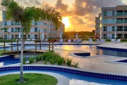 einem Pool mit einer Palme vor einem Gebäude in der Unterkunft Apartamento moderno, equipado e confortável in Porto De Galinhas