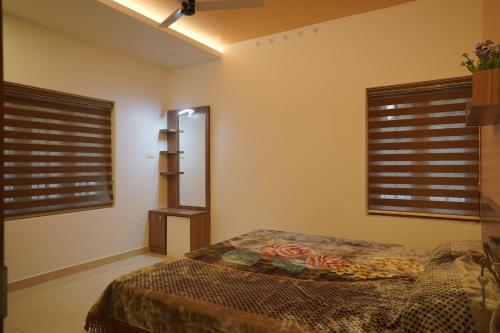 a bedroom with two windows and a bed in it at Luxury Homes - Cochin Airport - Nedumbassery in Angamaly