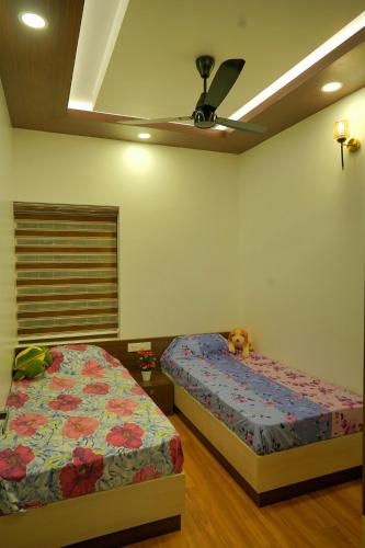 a bedroom with two beds and a ceiling fan at Luxury Homes - Cochin Airport - Nedumbassery in Angamali