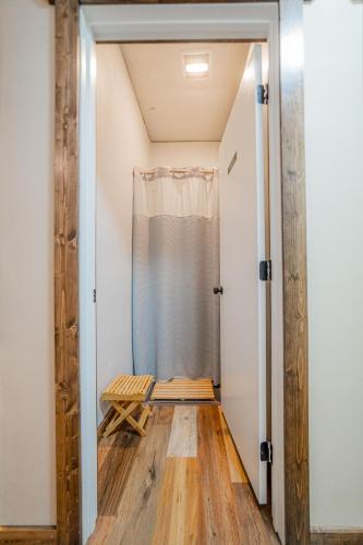 an open door to a room with a shower and a wooden floor at Pintler's Portal Hostel in Anaconda
