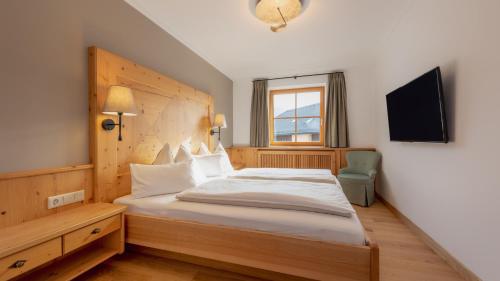 een slaapkamer met een groot bed met een houten hoofdeinde bij Wellnesshotel Eggerwirt in Sankt Michael im Lungau