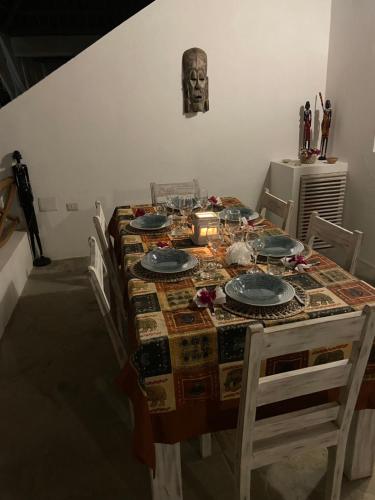 a dining room table with plates and a skull on the wall at Nakupenda House in Watamu