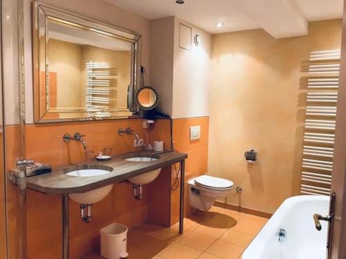 Hotel Daneu Gaschurn في غاسشرن: حمام مغسلتين ومرحاض ومرآة