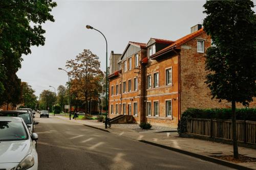 a street with cars parked next to a brick building at Old brick boutique apartments in Klaipėda