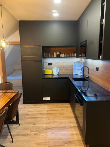 a kitchen with black cabinets and a wooden table at Apartman Horec 30 a 1 in Donovaly