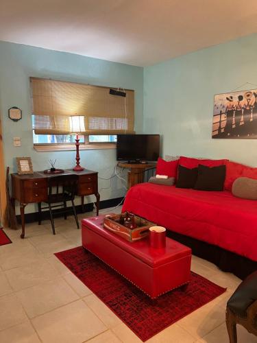 a living room with a red couch and a desk at Blue Bell Apartment Hotel in Fort Lauderdale