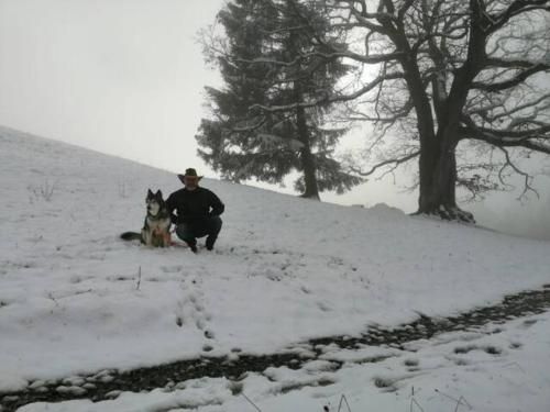 a man and a dog sitting in the snow at Wohnung Rheintal im Alpenvorland in Batschuns
