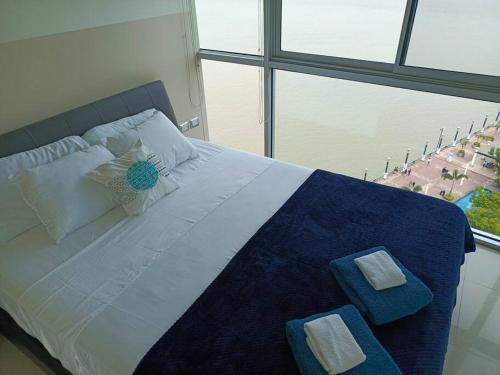 a bedroom with a large bed with two towels on it at Riversuits#1 Santa Ana in Guayaquil