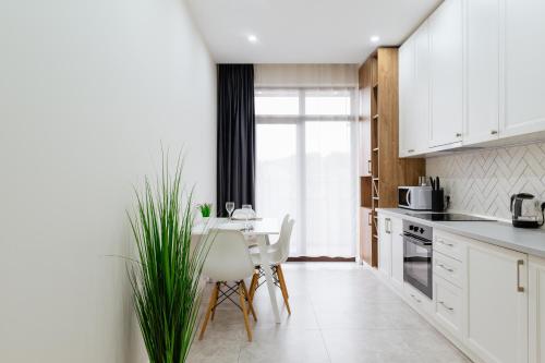 a kitchen with white cabinets and a table and chairs at Luxury Apartments “Dream City” in Uzhhorod