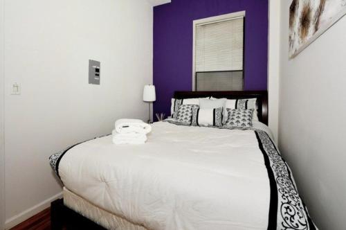 a bedroom with a large white bed with purple walls at The Luxe Loft 4BR Apartment in NYC! in New York