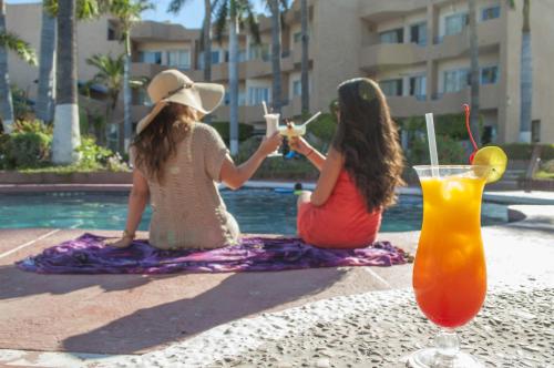 duas raparigas sentadas ao lado de uma piscina com bebidas em Hotel Hacienda Tetakawi em San Carlos