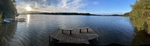 a lake with a wooden dock in the middle of it at Karmelowe Domki Kaszuby, z jacuzzi na tarasie z widokiem na jezioro in Stężyca